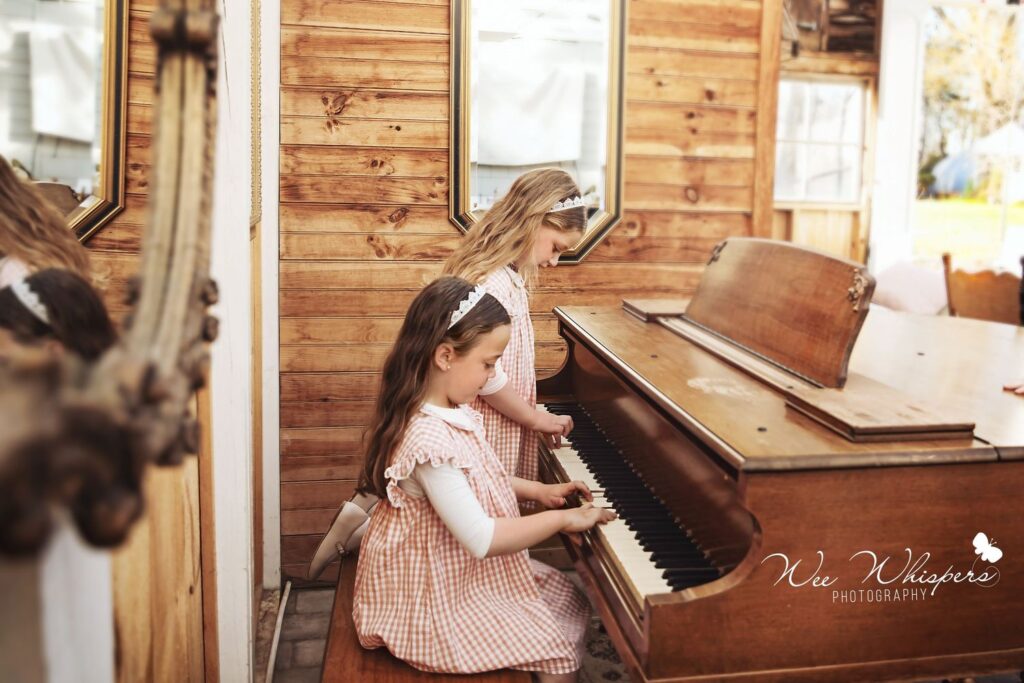 two girls are playing piano and the photograph is taken by wee whispers
