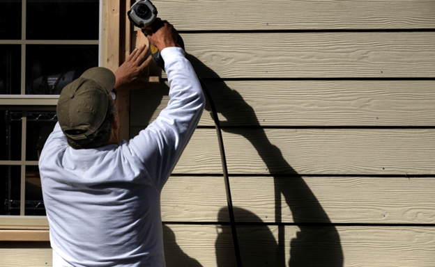 A worker is making siding on a home