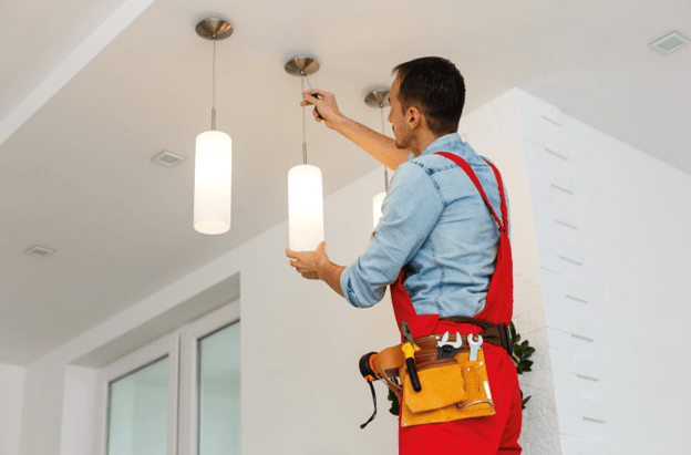 An electrician is fixing a hanging roof lamp