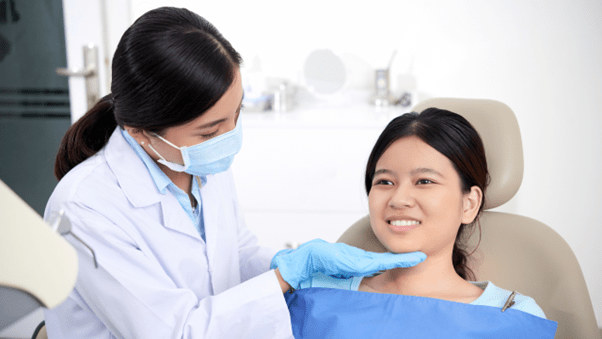 A lady doctor is touching a lady patients chin after orthodontic treatment